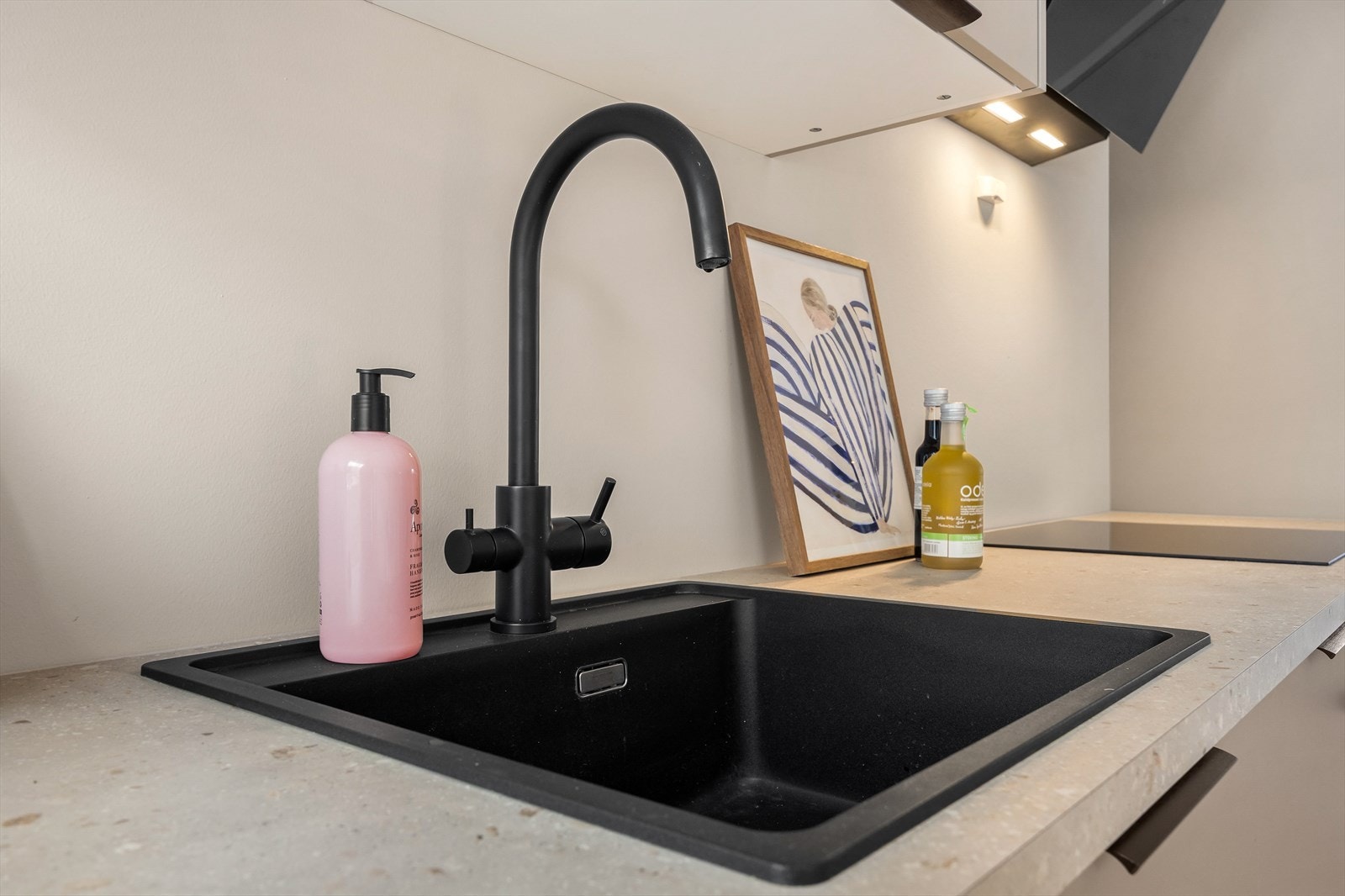 Detaljer som nedfelt kum og ett-greps kran i sort utførelse understreker den gjennomførte stilen. Galleribilde