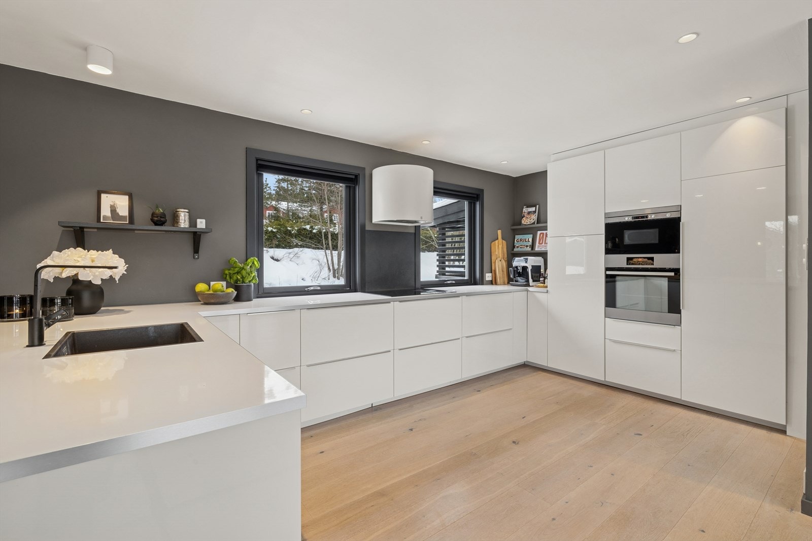 Moderne kjøkkeninnredning med glatte, hvite fronter (2015) og rikelig med skap- og benkeplass. Galleribilde