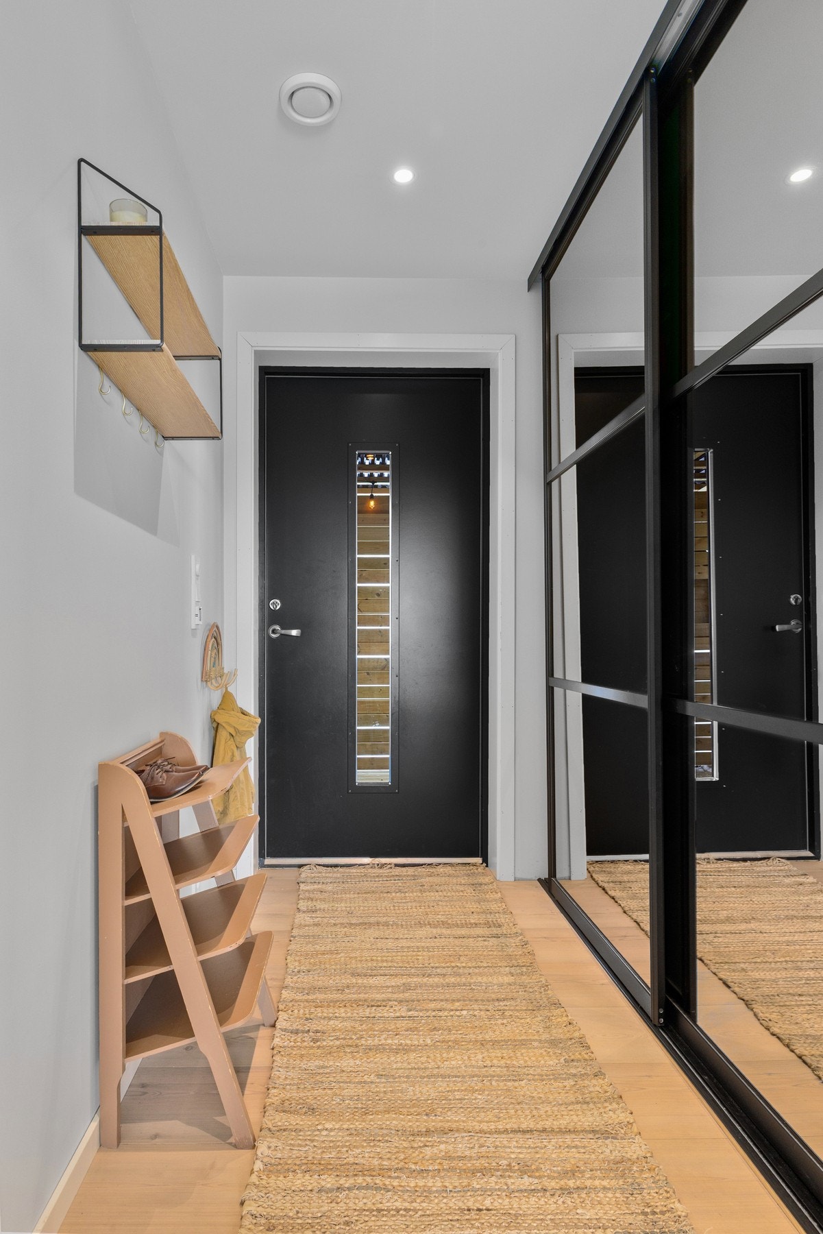 En romslig og innbydende entré med skyvedørsgarderobe og praktisk innredningsløsning fra Elfa, som gir svært gode oppbevaringsmuligheter. Varmefolie i gulvet sørger for behagelig komfort året rundt. Foto: Marte Vibe Galleribilde