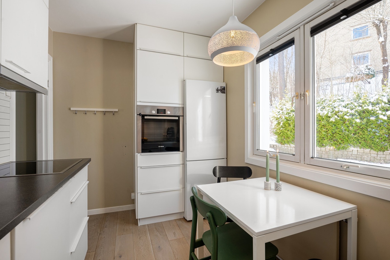 Kjøkken med spiseplass og utsikt over bakhagen - integrerte hvitevarer og frittstående kjøleskap Galleribilde