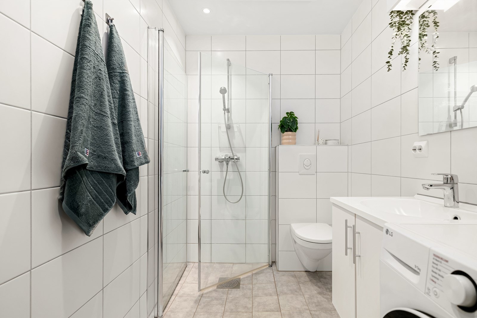 Badet har et nedsenket dusjhjørne med svingbare dører og praktisk opplegg for vaskemaskin. Galleribilde