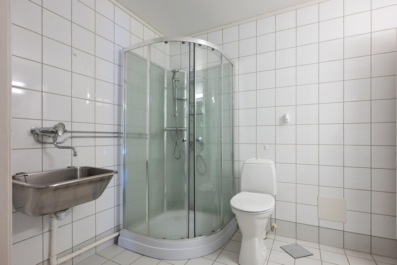 Badet er innredet med vegghengt servant, speil, høyskap, frittstående toalett, skyllekar og dusjkabinett. Galleribilde