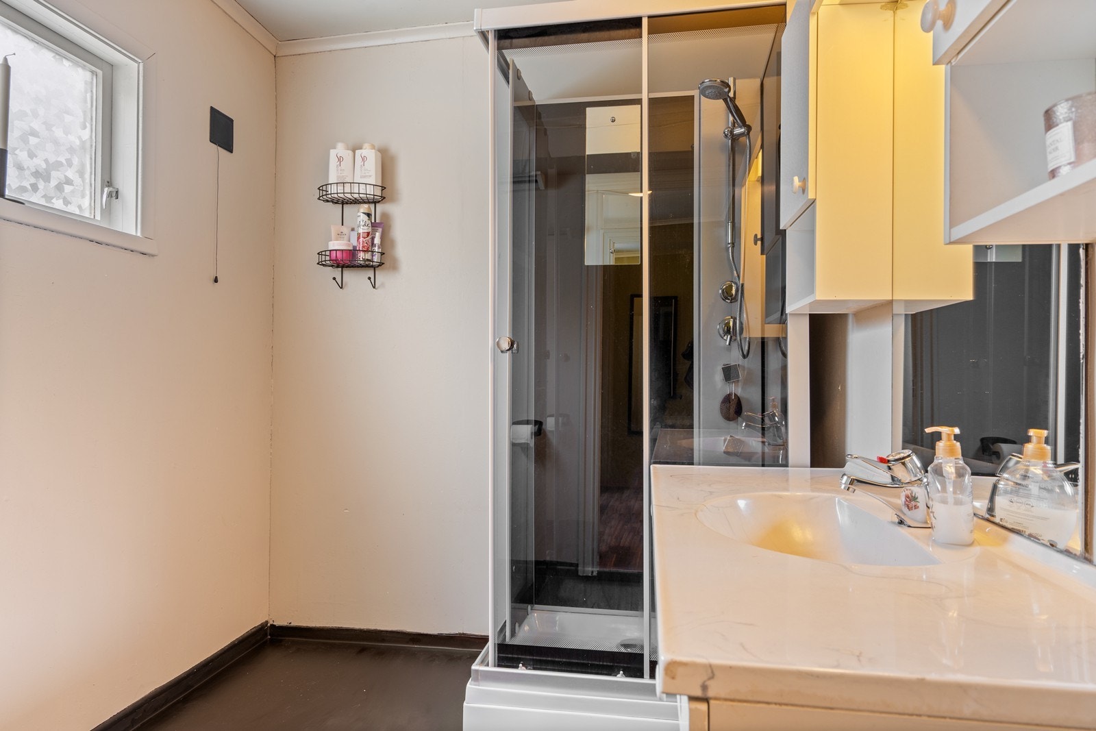 Badet inneholdere dusjkabinett, toalett og servant i møblement med speil og belysning. Galleribilde