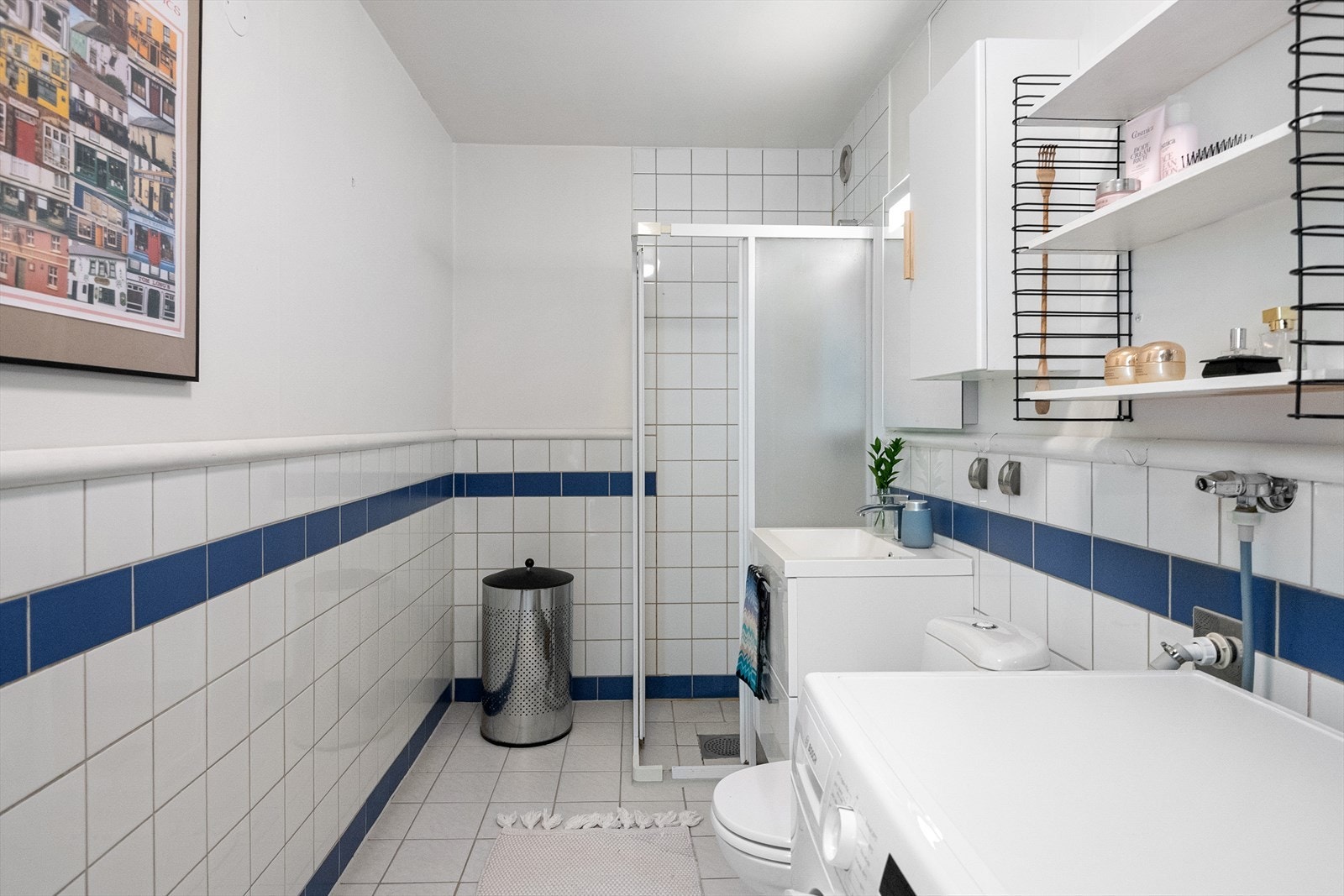 Flislagt baderom med servantinnredning, speil med belysning og praktisk oppsett. Galleribilde