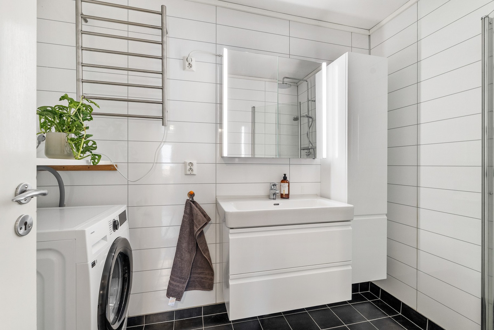 Bad med baderomsplater på veggene og flislagt gulv med varmekabler. Galleribilde