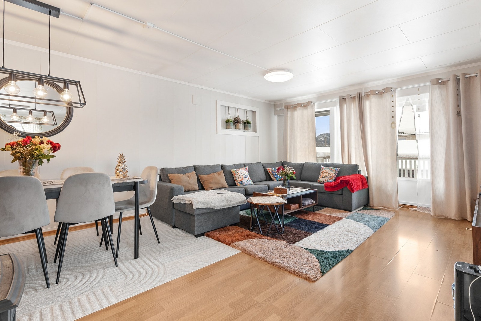 Romslig stue med laminatgulv, plater på vegger og takplater i himling Galleribilde