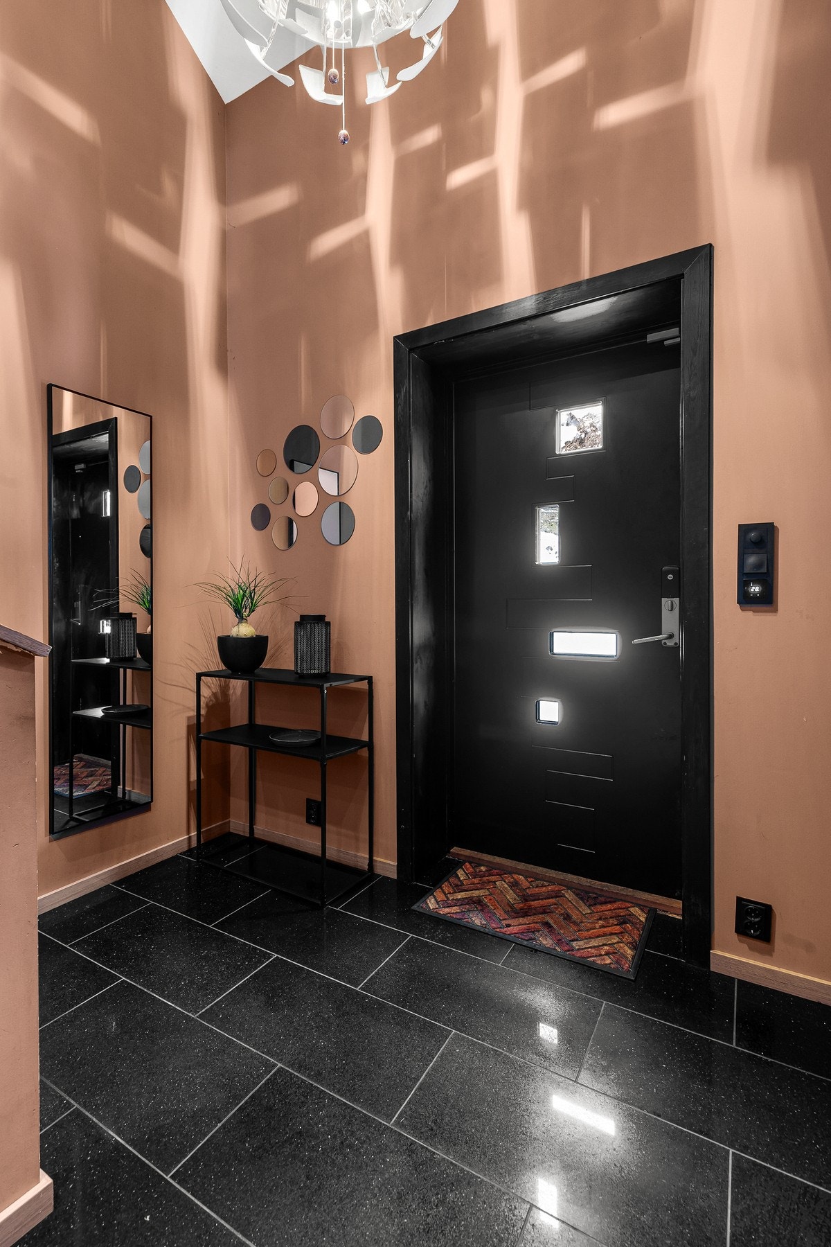 Romslig entré/trappegang med flislagt gulv og slette vegg- og himlingsflater Galleribilde