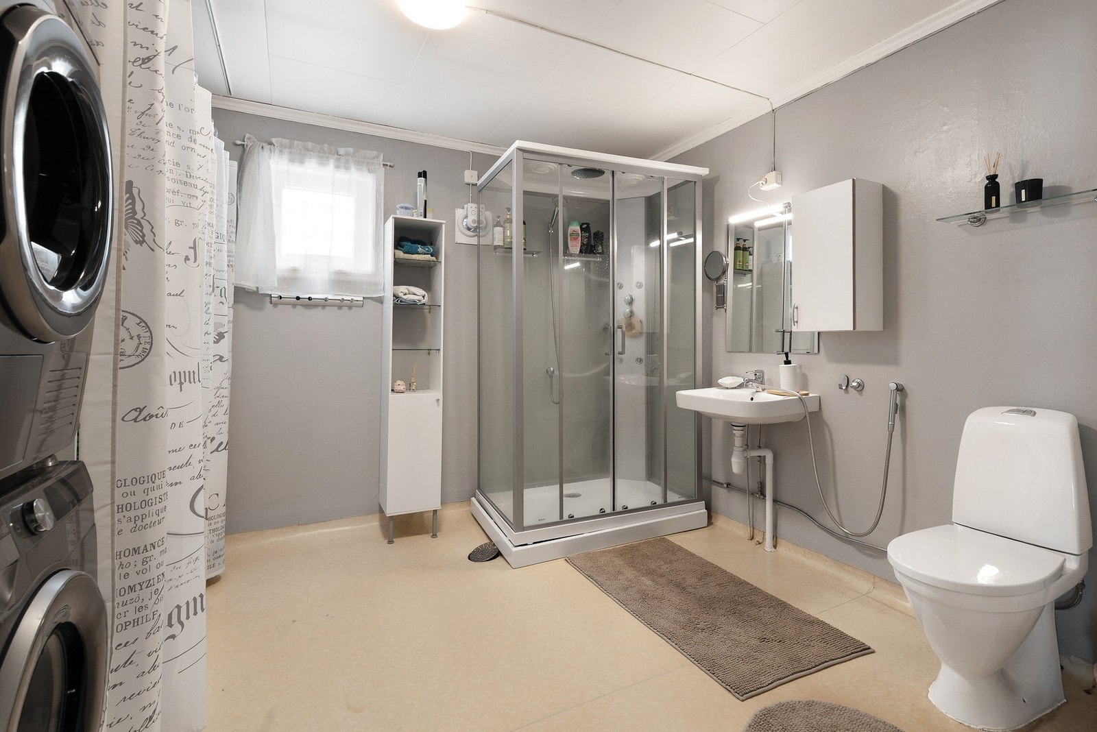 Bad med vinylbelegg på gulv, malte flater på vegger og takplater i himling. Innredet med toalett, servant, dusjkabinett og opplegg for vaskemaskin Galleribilde