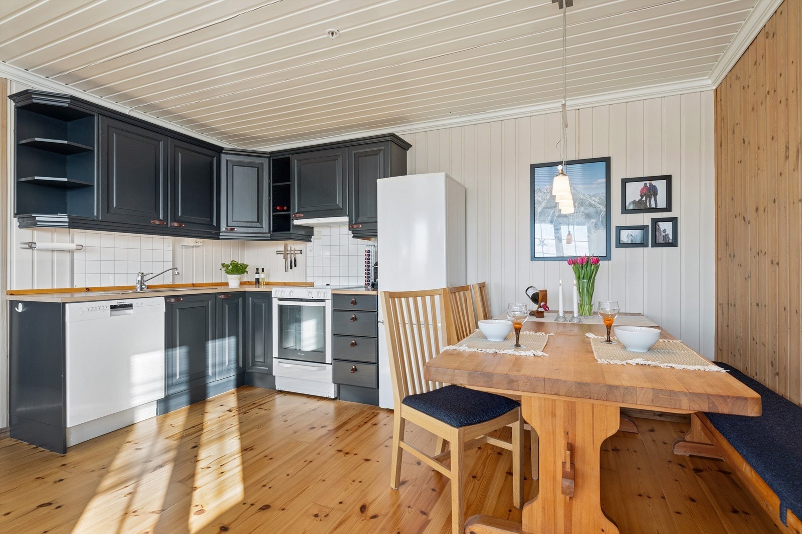 Kjøkken i furu med profilerte, malte skapdører i dempet sort gir en lun og gjennomført karakter. Galleribilde