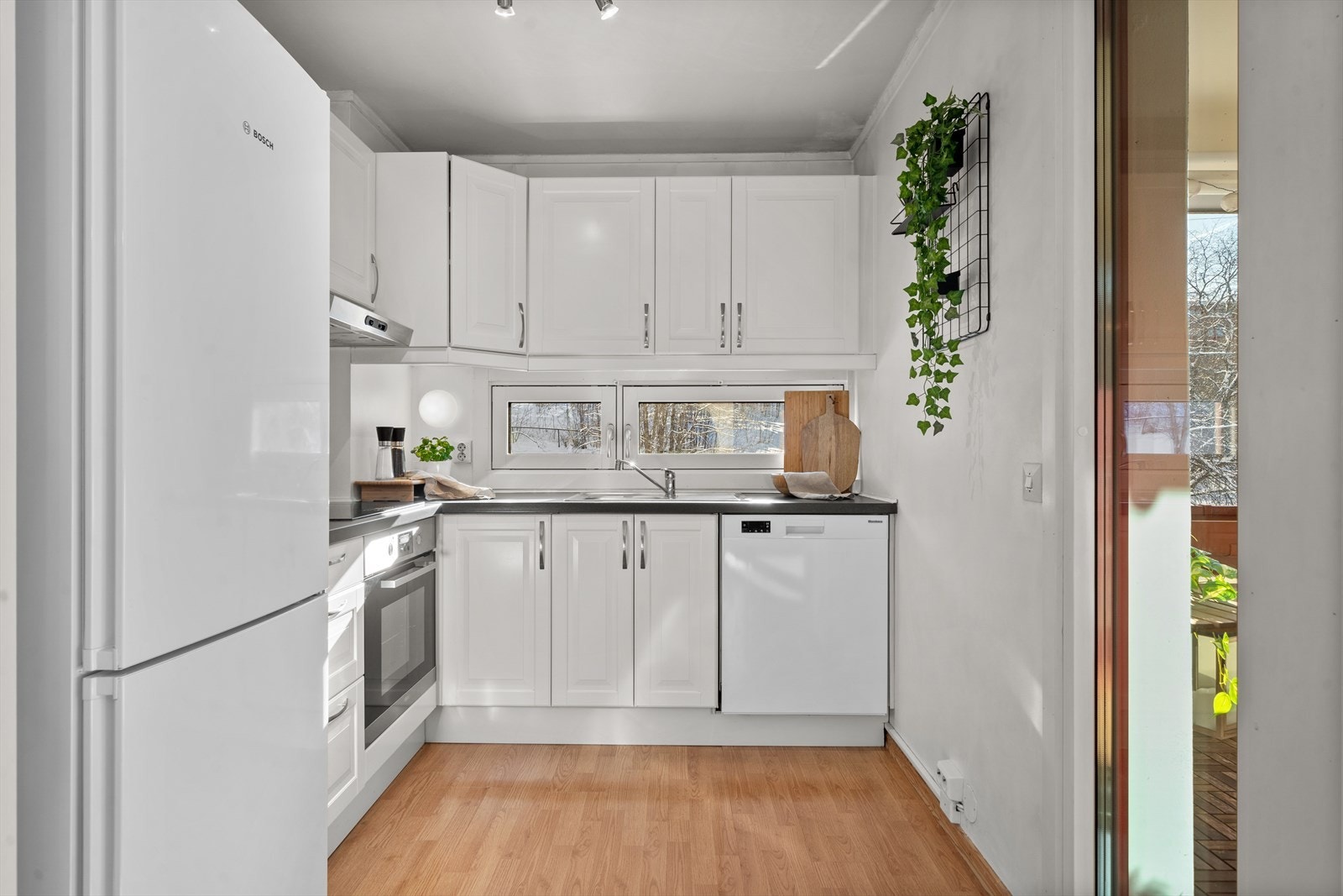 Lyst og pent kjøkken med profilerte fronter og benkeplate i laminat. Hvitevarer er delvis integrerte. Galleribilde