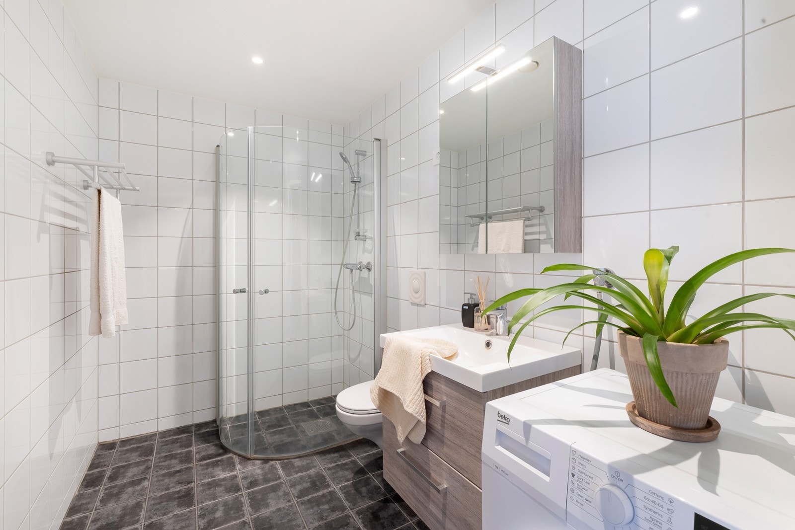 Badet har dusj, vegghengt toalett og servant m/ underskuff og speilskap (innredning fra 2023) Galleribilde