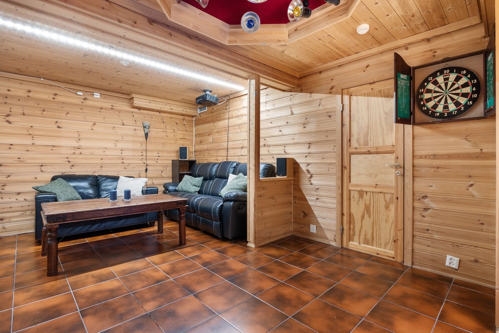 En stor kjellerstue på 26,4 kvm med fliser på gulvet åpner opp for muligheter som lekerom, treningsområde eller en uformell TV-stue. Galleribilde