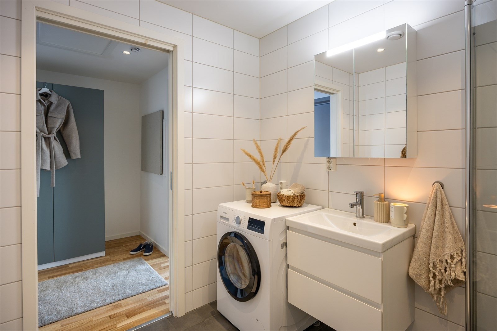 Badet er utstyrt med vegghengt toalett, innredning med servant, dusjvegger av glass og opplegg for vaskemaskin. Galleribilde