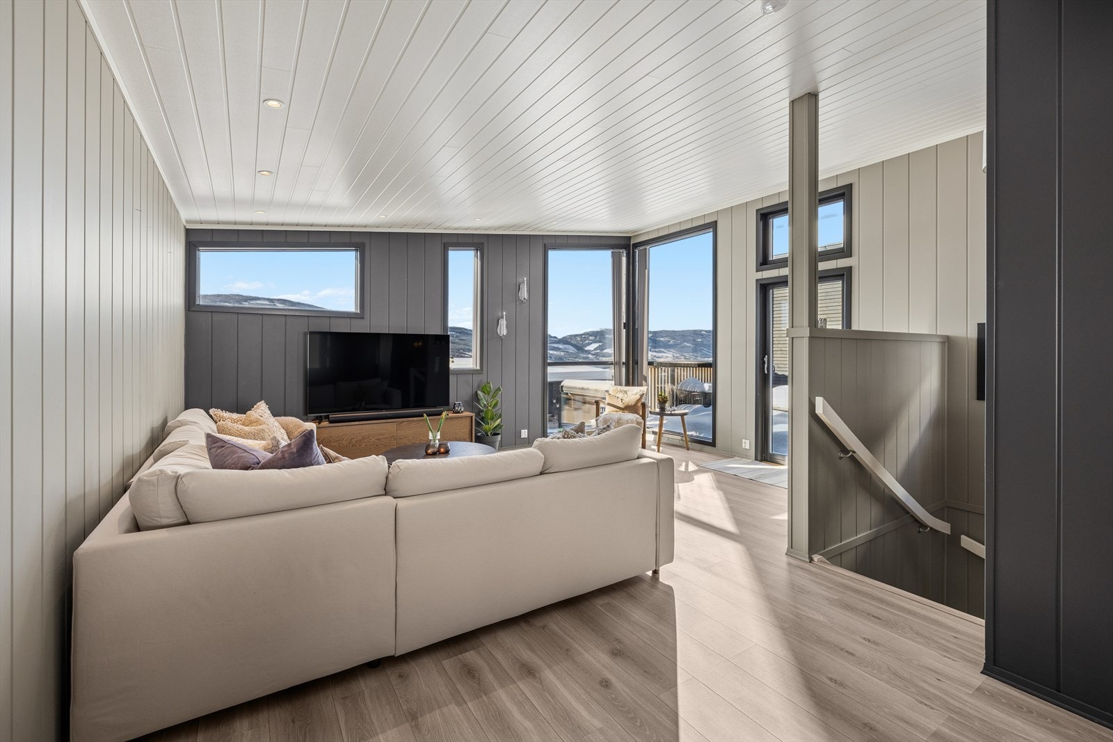 Stuen har laminat på gulv, panel på veggene som er malt i moderne farger og downlights i tak. Galleribilde