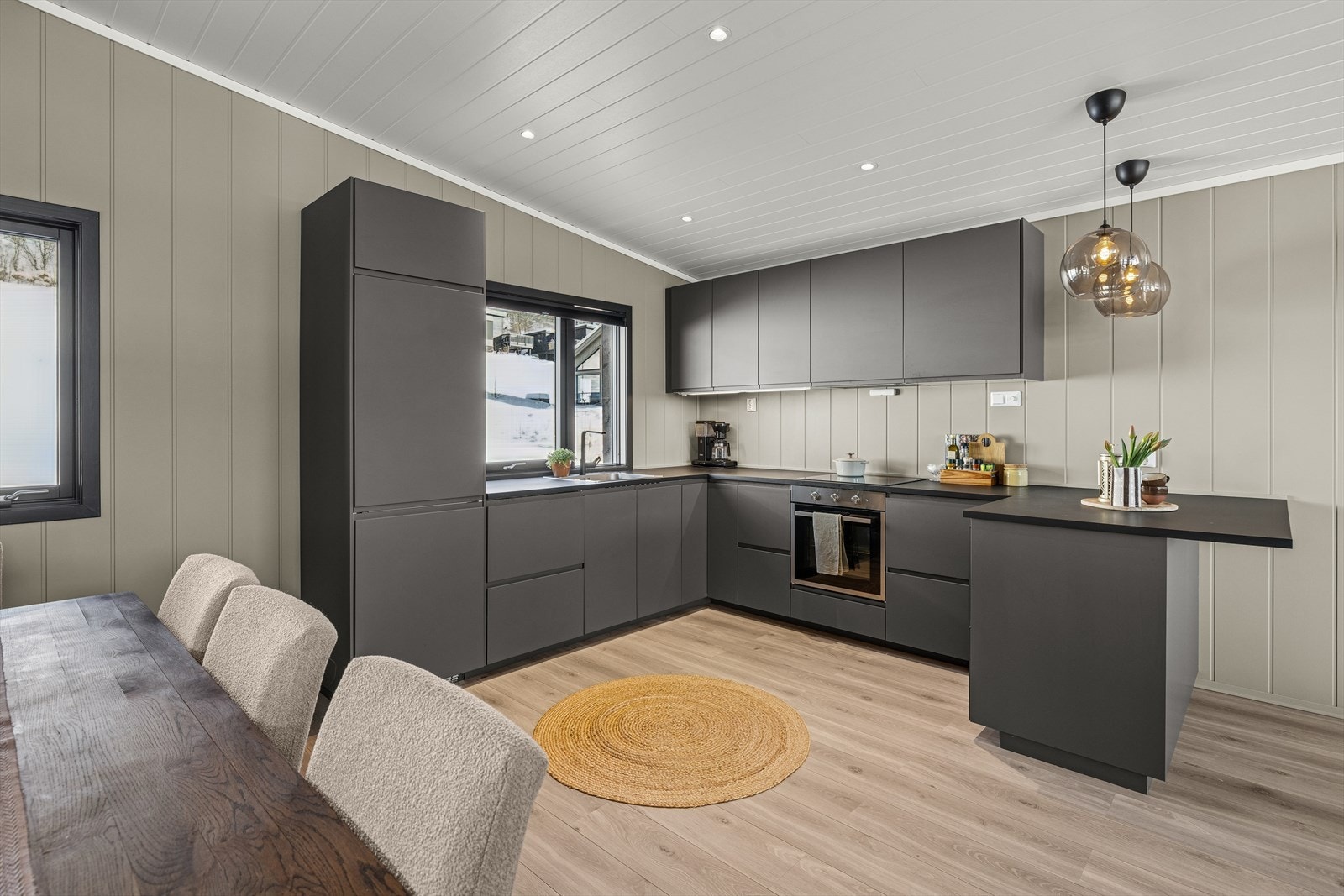 Lekkert kjøkken med mørke fronter og laminert benkeplate med kjøkkenkum. Galleribilde