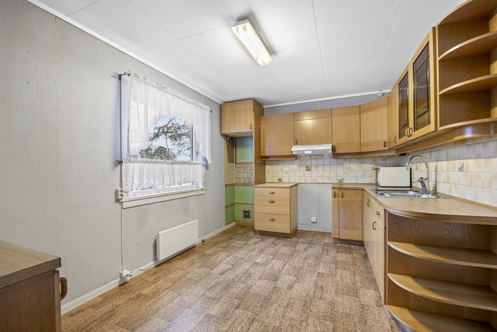 Kjøkkenet har en eldre, funksjonell innredning med slette fronter og laminert benkeplate. Galleribilde