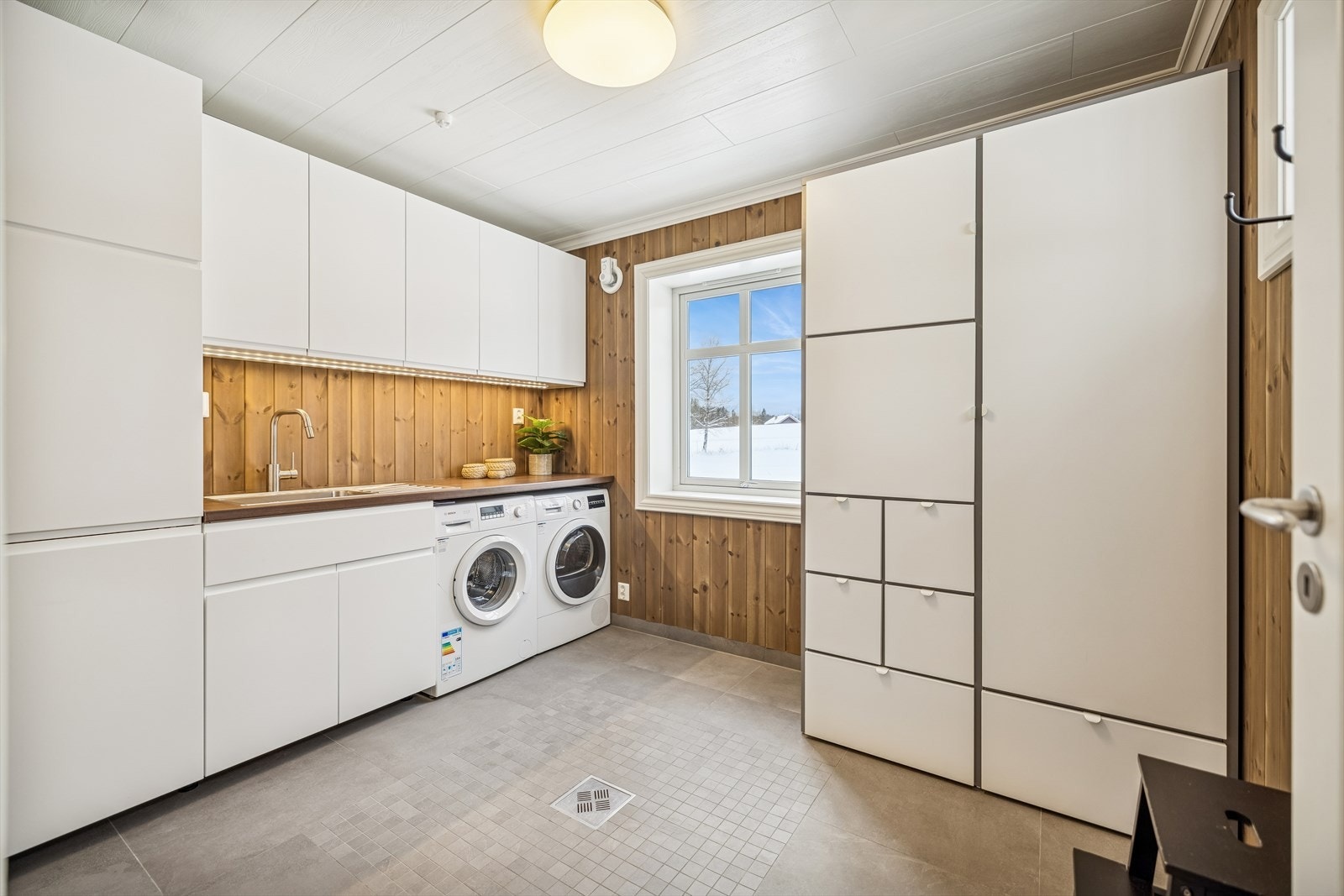 Praktisk vaskerom fra 2017 med flislagt gulv, vannbåren gulvvarme og opplegg for vaskemaskin. Galleribilde