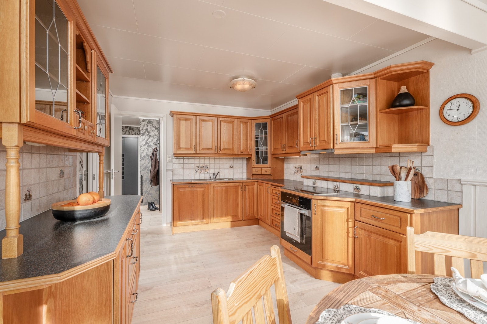 Kjøkkenet har integrerte hvitevarer, flislagt vegg mellom over og underskap og pene blyglass i noen av overskapene. Galleribilde