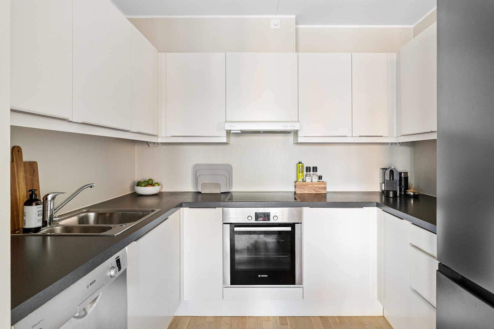 Kjøkkenet har lys, glatt innredning med laminat benkeplate, nedfelt oppvaskkum og ett-greps armatur. Galleribilde