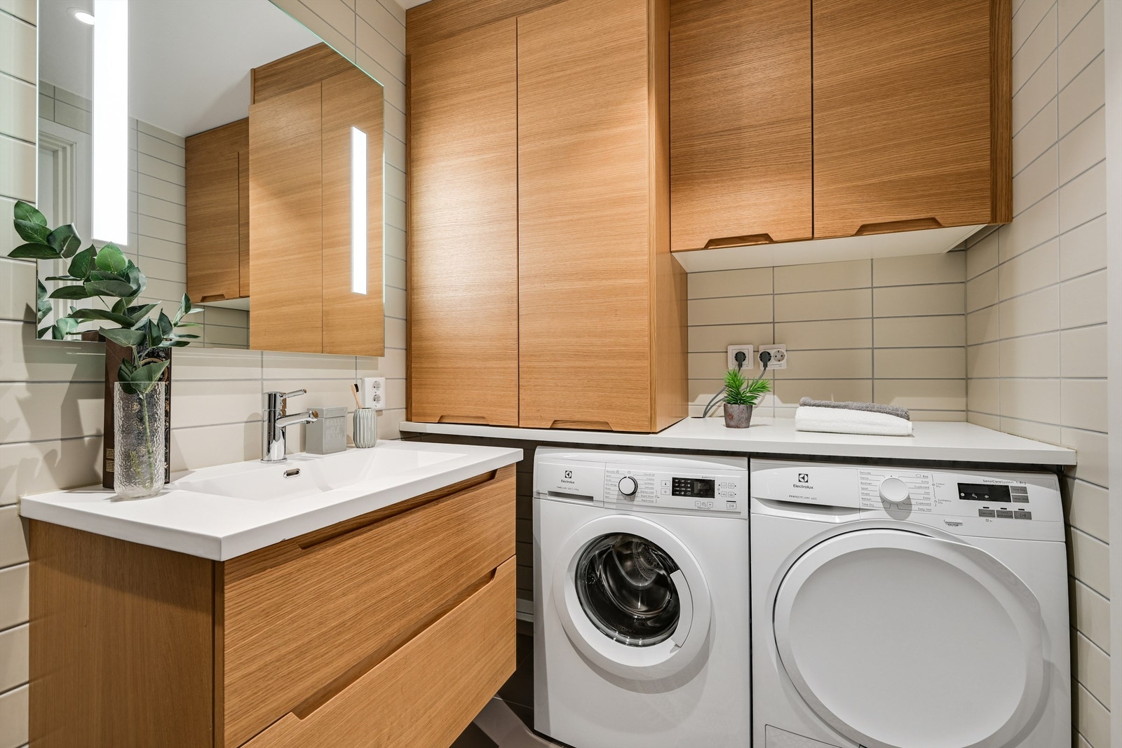 Plassbygget innredning med plass til vaskemaskin og tørketrommel, samt lekker skapløsning og benkeplate som gir et eksklusivt og svært praktisk inntrykk. Galleribilde