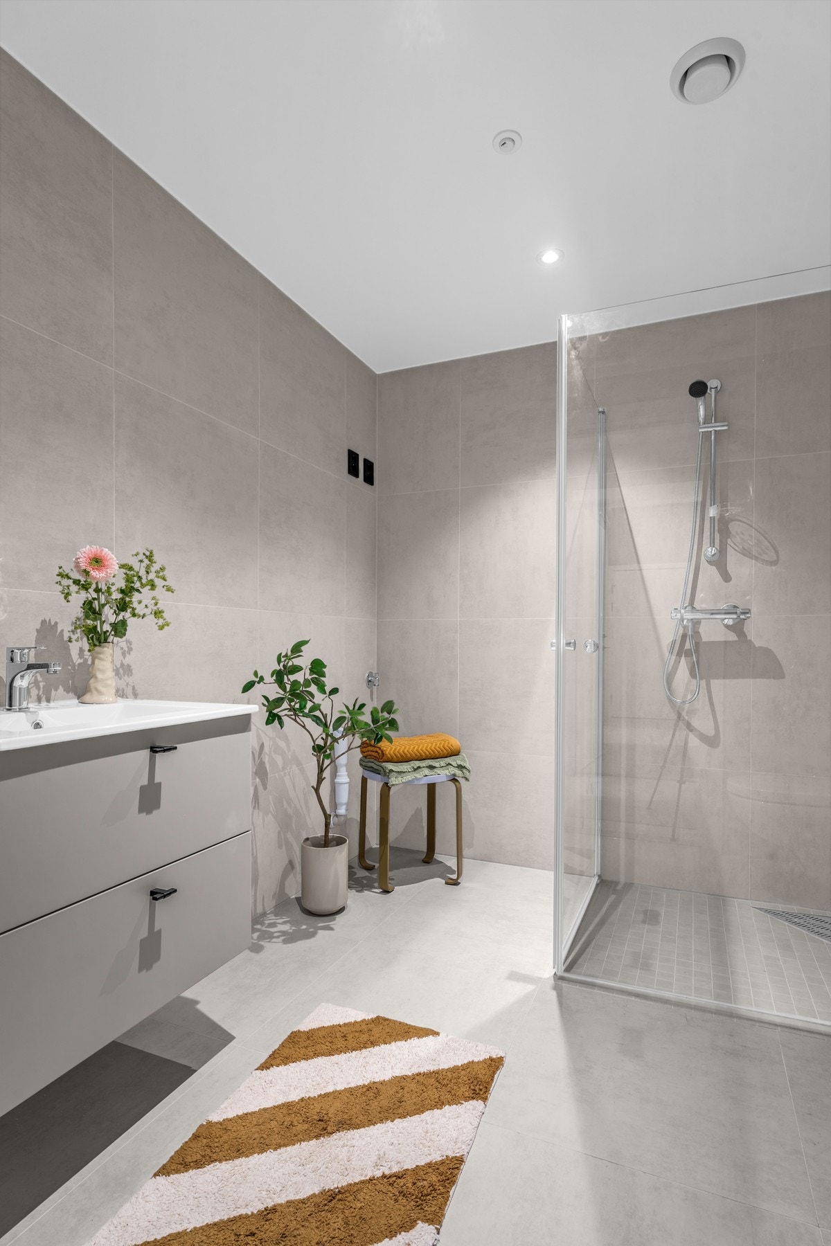 Plassbygget bad med stilren servantinnredning fra Strai og dusjsone med glassvegger. Galleribilde