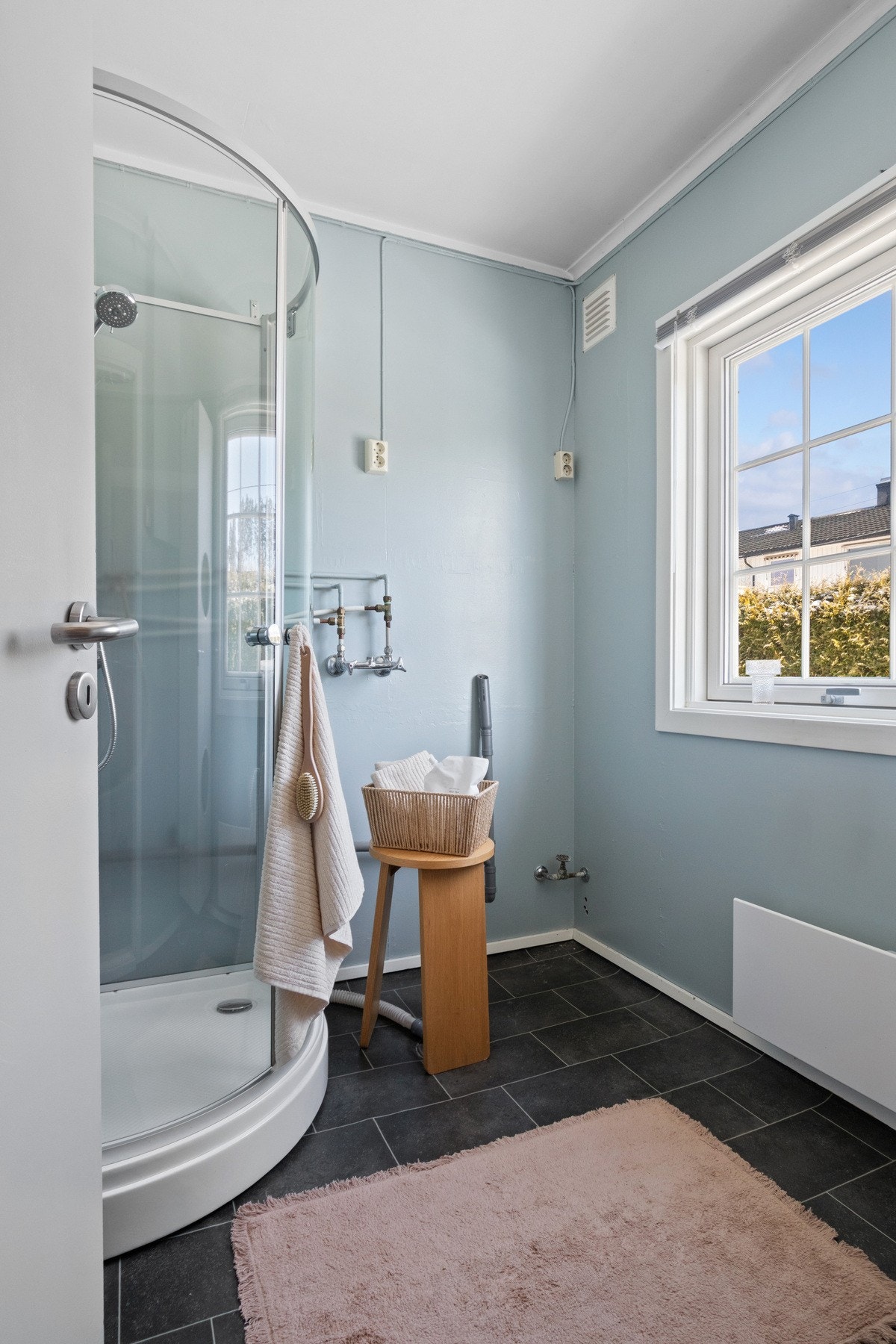 Det er opplegg for vaskemaskin og tørketrommel i søyleløsning. Det er laminat på gulvet og veggene er malt i blå tone. Galleribilde