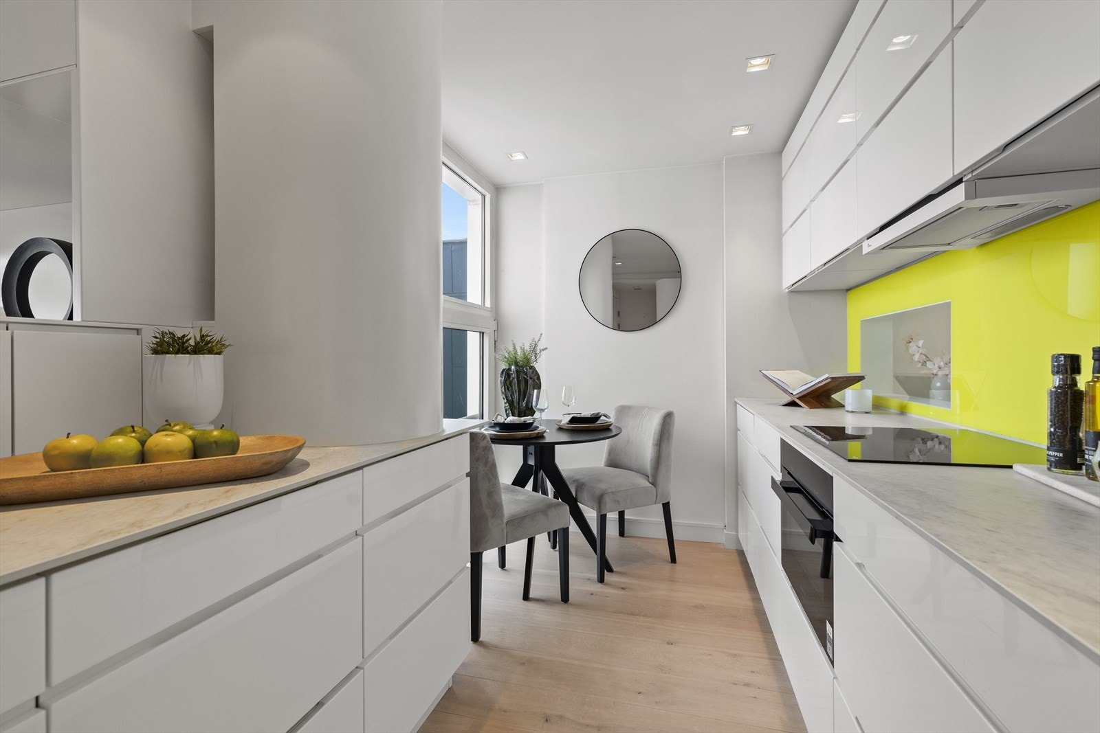 Kjøkkeninnredning med hvite glatte fronter og benkeplate i stein. Galleribilde