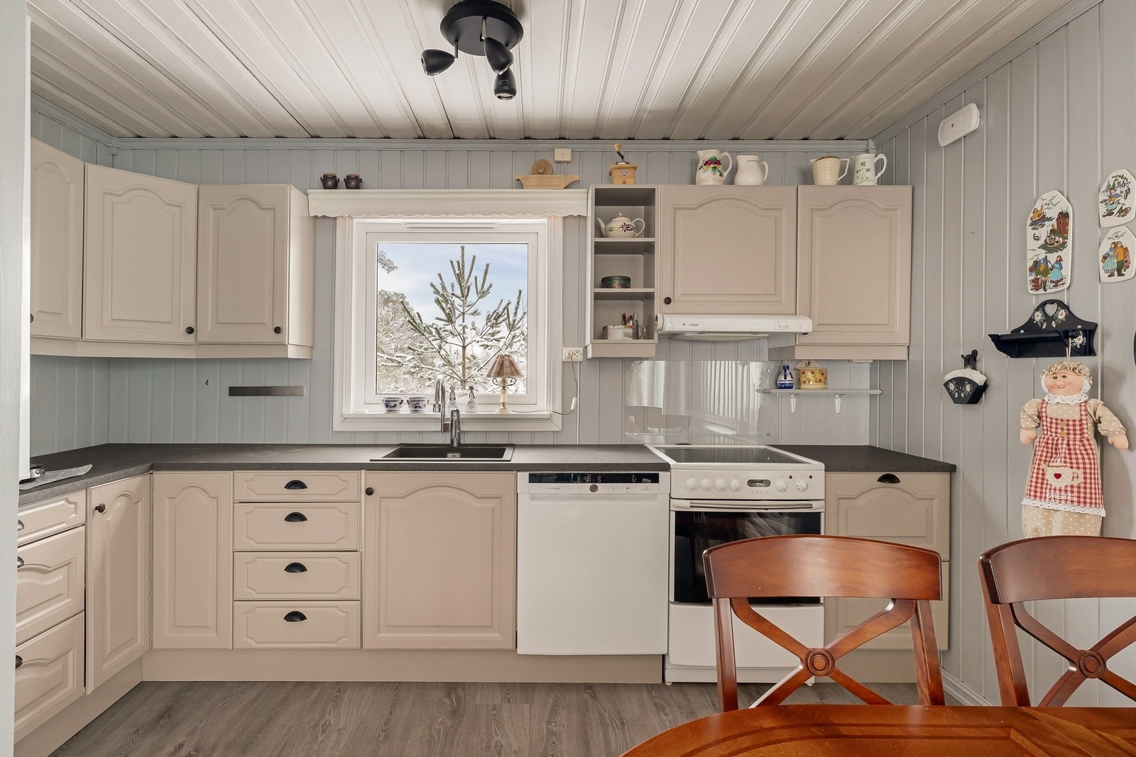 Kjøkkeninnredningen med malte fronter, ventilator og vask har rikelig med benkeplass, skap og skuffer. Galleribilde