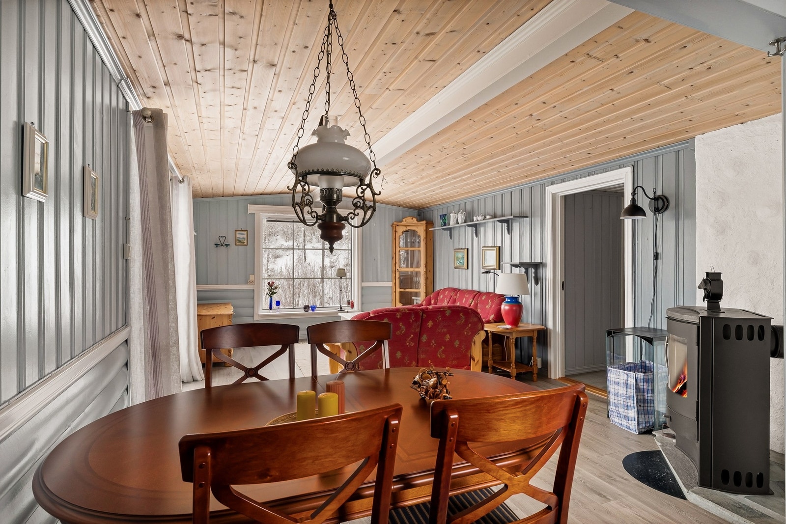 Stua med åpen løsning til kjøkkenet har god plass til både spisebord og sofakrok. Peisovnen er plassert slik at flammene kan sees fra begge steder. Galleribilde