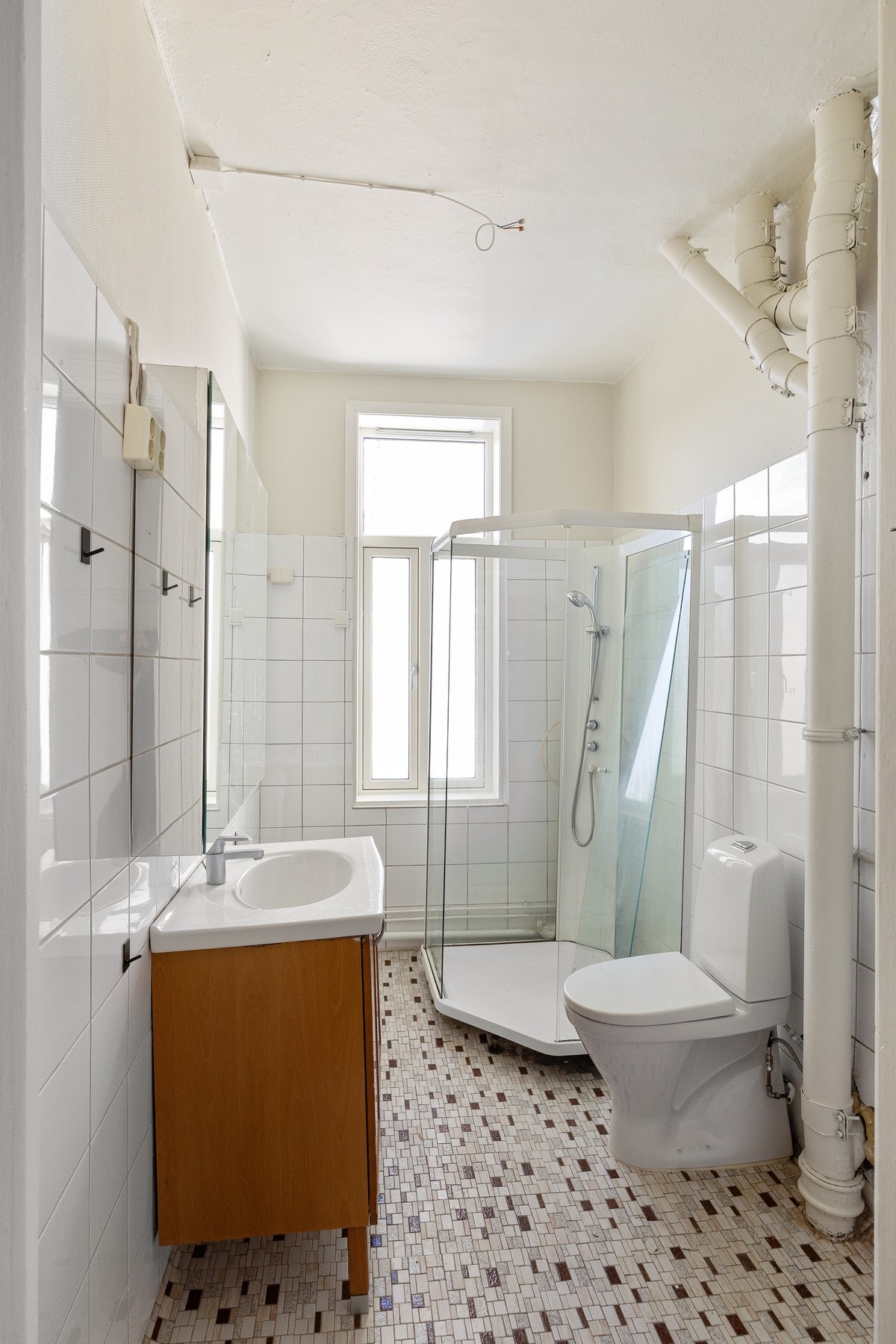 Romslig baderom med lyse overflater og vindu. Galleribilde