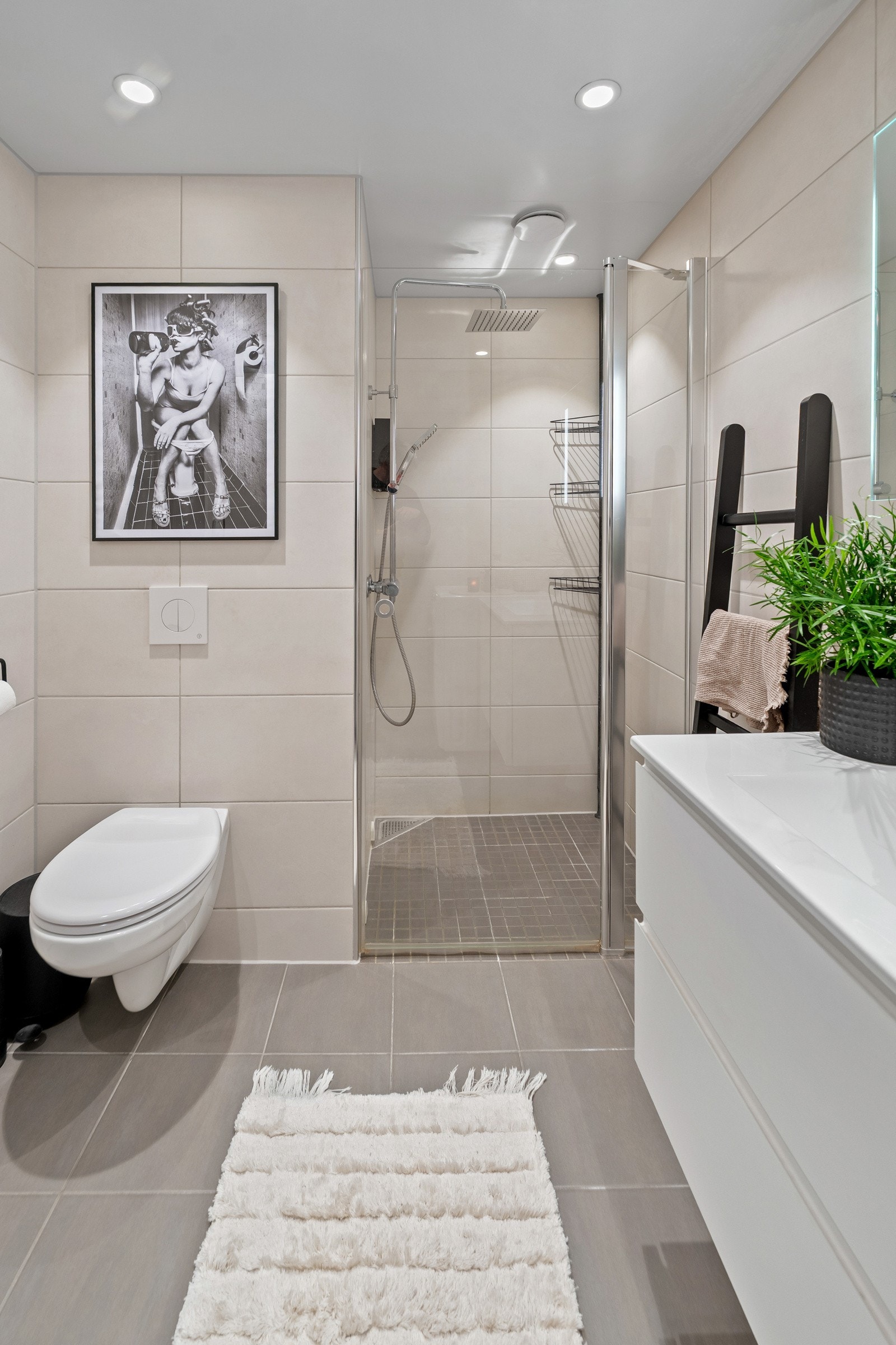 Stort dusjhjørne med glassdører, speil med integrert belysning og god oppbevaringsplass i servantskap. Galleribilde