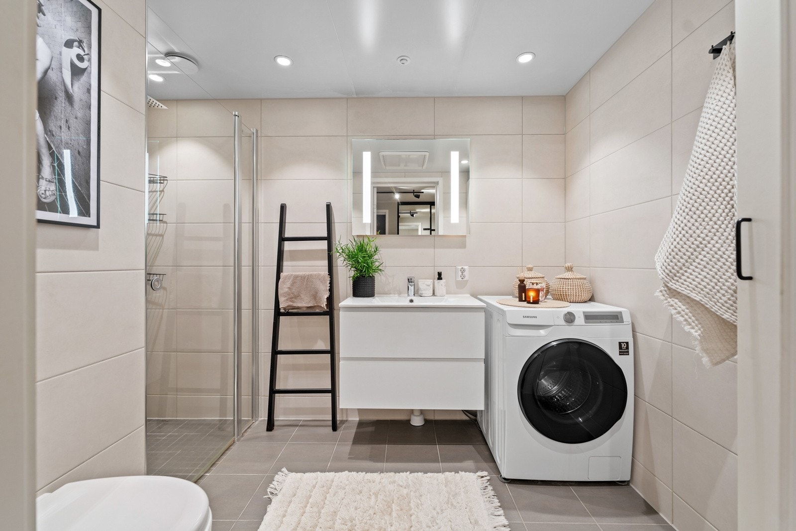 Romslig og moderne bad med flislagte overflater, behagelige varmekabler i gulv og opplegg for vaskemaskin. Galleribilde