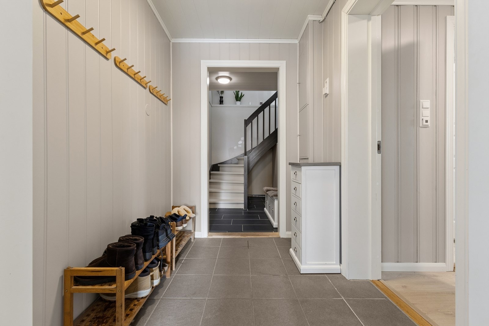 Inngang via vindfang med flislagt gulv, som leder videre inn i en gang. Galleribilde