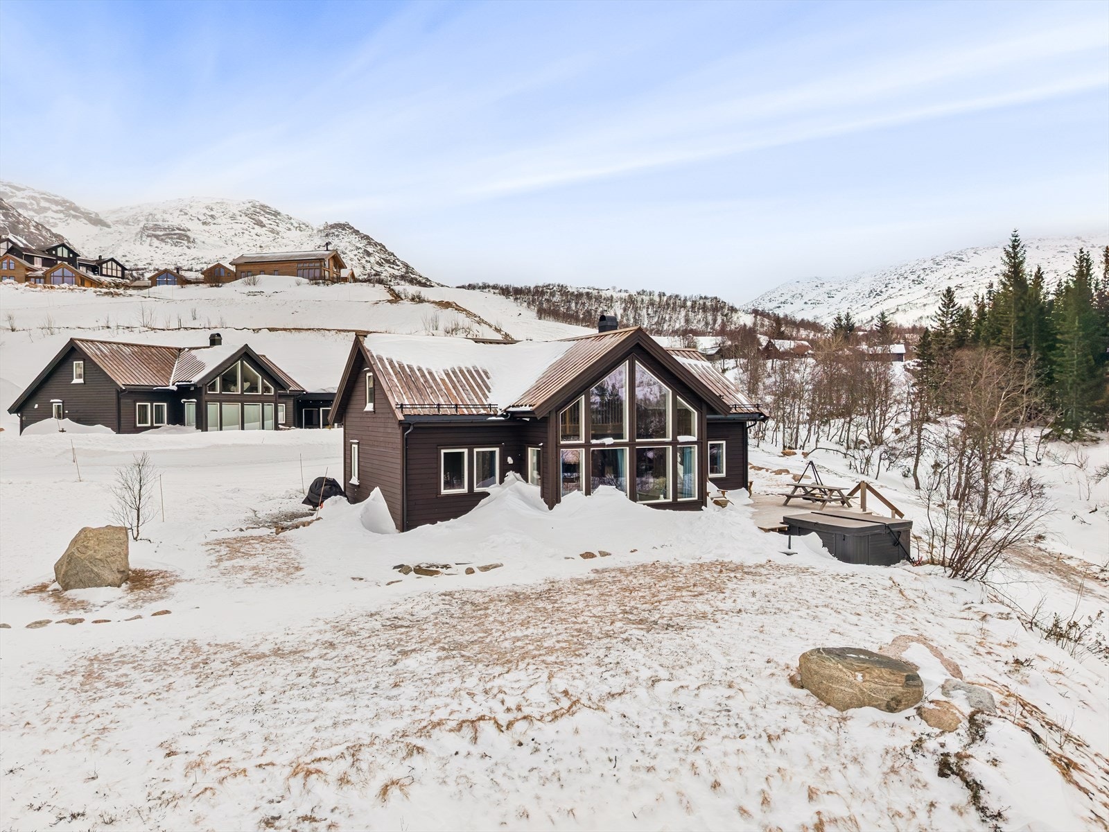 Flat og pent opparbeidet tomt med steinheller, terrasse og plen. Galleribilde