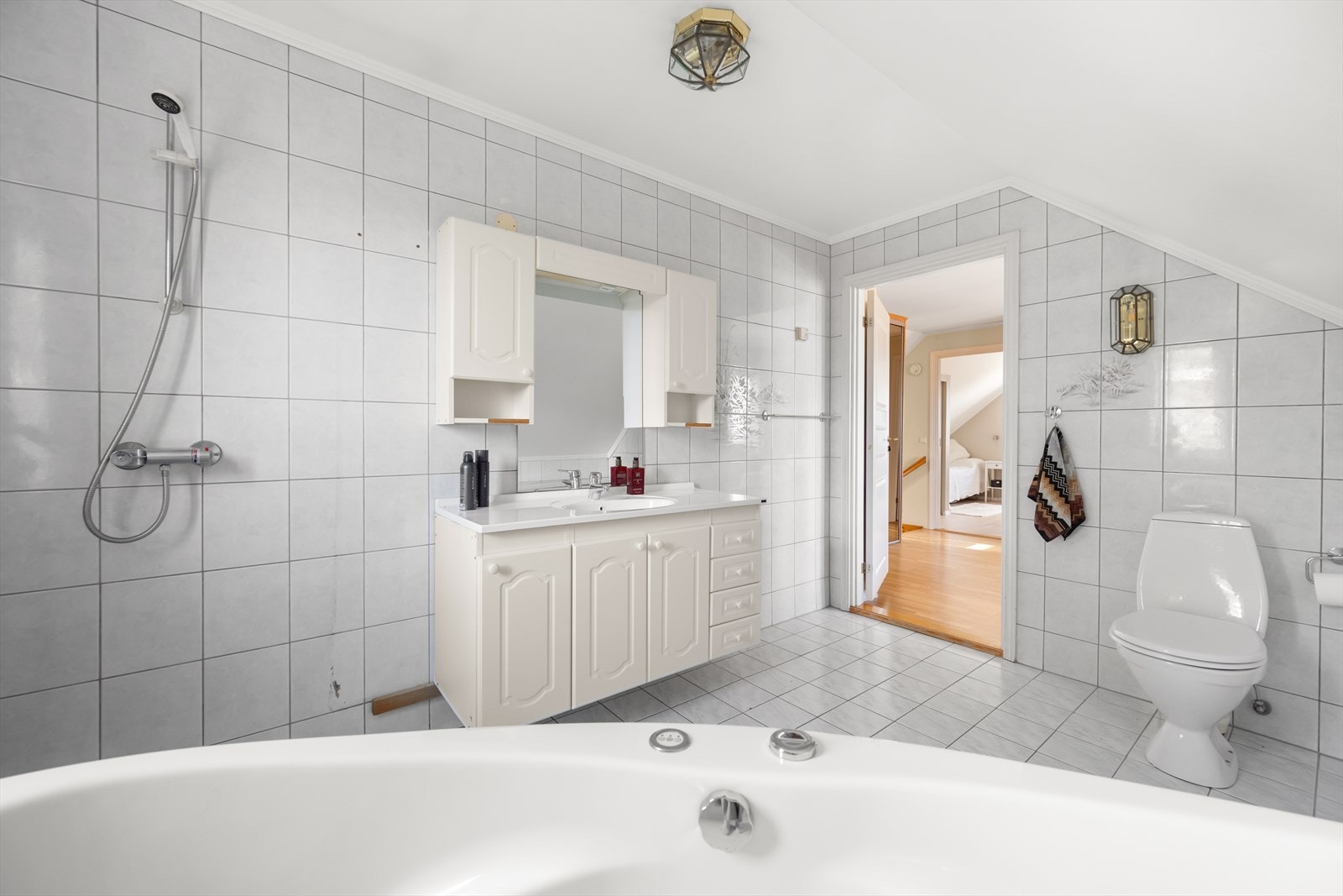 Bred baderomsinnredning med skuffer, skap, nedfelt servant og vegghengt speil. Galleribilde