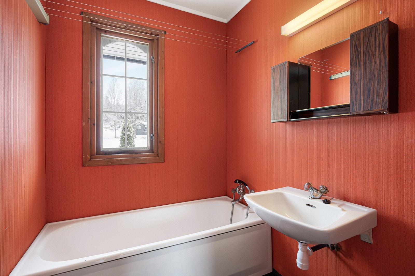 Badet og wc-rommet ligger vegg-i-vegg i første etasje, og har behov for modernisering for å oppnå dagens krav til standard. På badet er det røde, tapetserte vegger og koksgrått gulvbelegg. Galleribilde