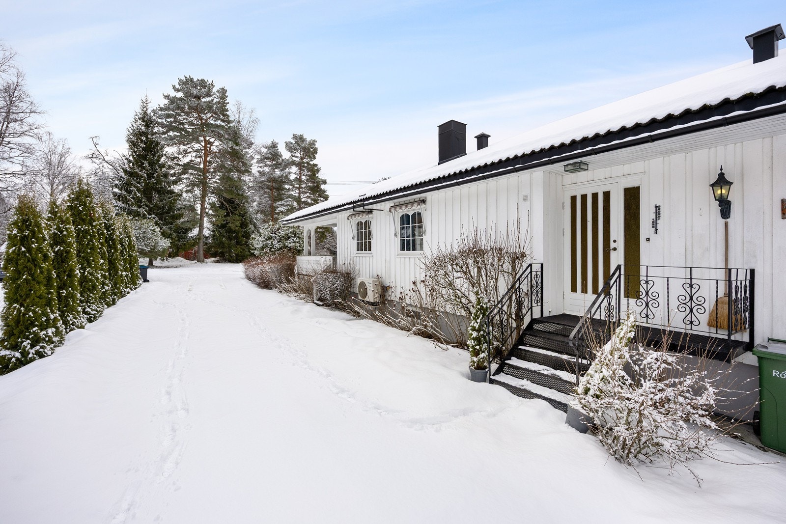 Eneboligen har et pent, overbygd inngangsparti med gruslagt adkomst, sortlakkert ståltrapp og klassisk utebelysning. Galleribilde