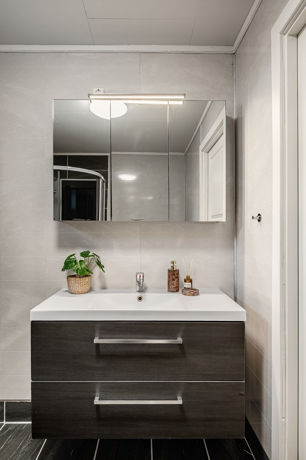 Pen baderomsinnredning med skuffer og heldekkende servant, speilskap med belysning over. Galleribilde