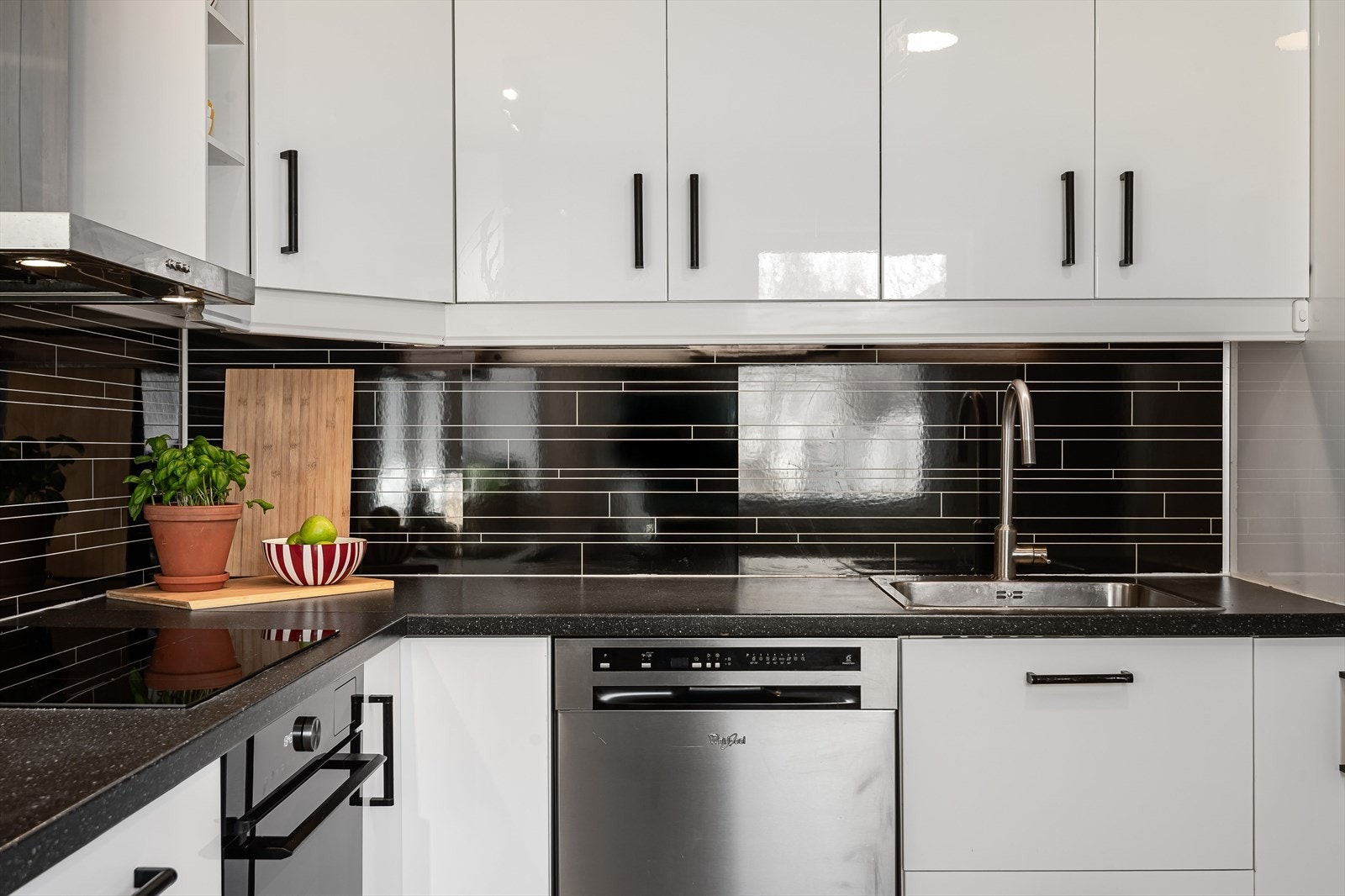 Praktisk med sorte flisimitasjonsplater i benkeryggen og belysning under overskapene. Galleribilde