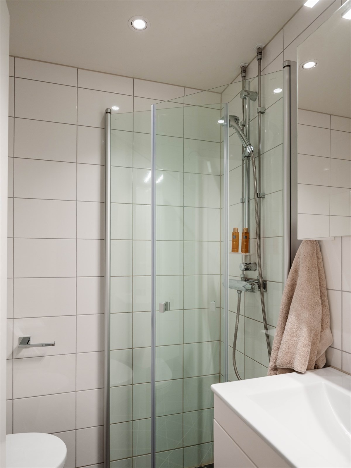 Badet er utstyrt med vegghengt klosett og et dusjhjørne med svingbare glassdører. Galleribilde