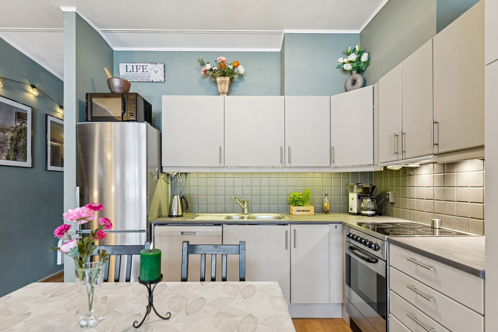 Kjøkkeninnredningen har glatte fronter, malt laminat benkeplate og malte fliser over kjøkkebenk. Galleribilde