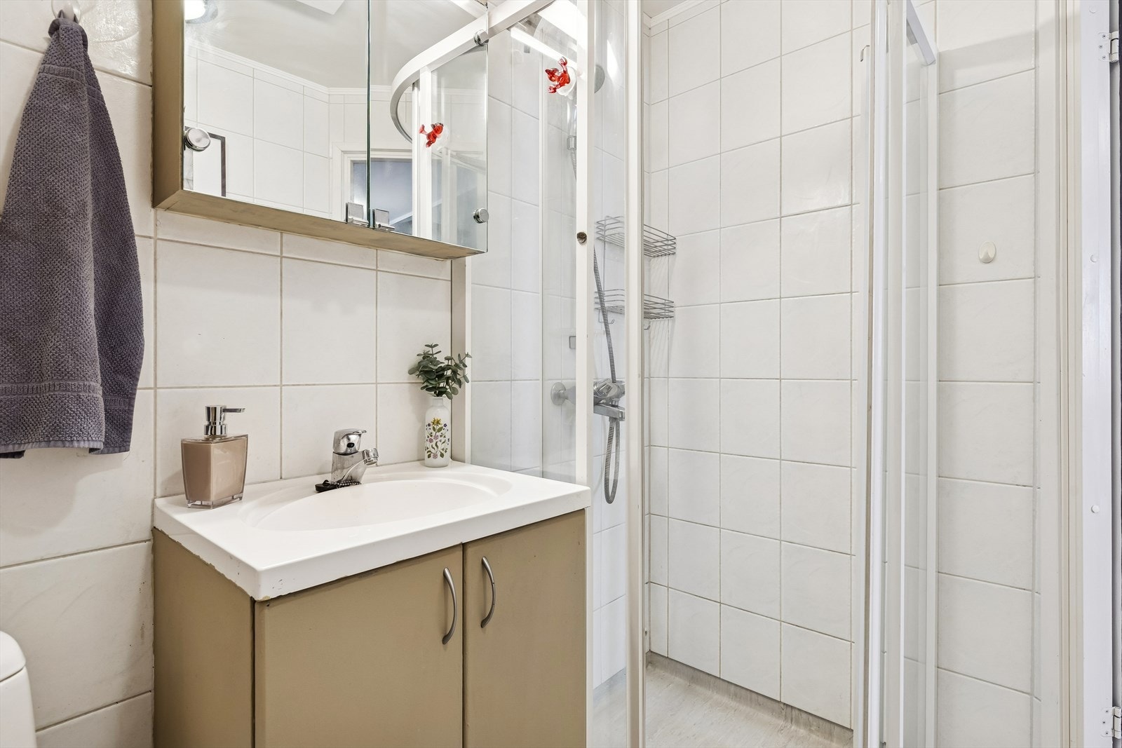 Badet har gulvstående toalett, heldekkende servant i skapinnredning og dusjkabinett med skyvedører. Det er også opplegg for vaskemaskin på badet. Galleribilde