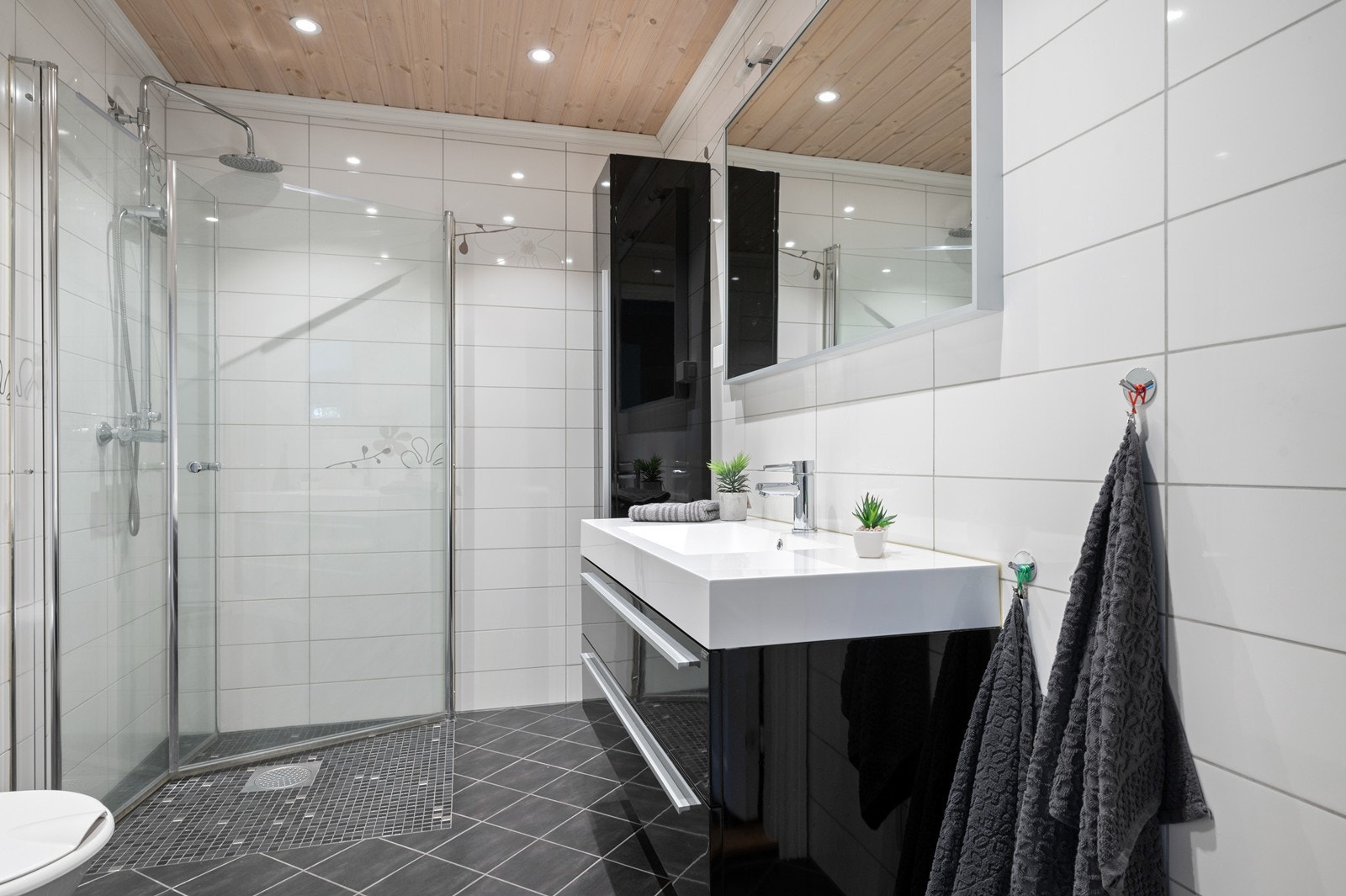 Helfliset bad, som ble modernisert i 2013, i klassiske og tidløse farger, med mørke gulvfliser, lyse veggfliser og en romslig dusjnisje med glassdører. Galleribilde