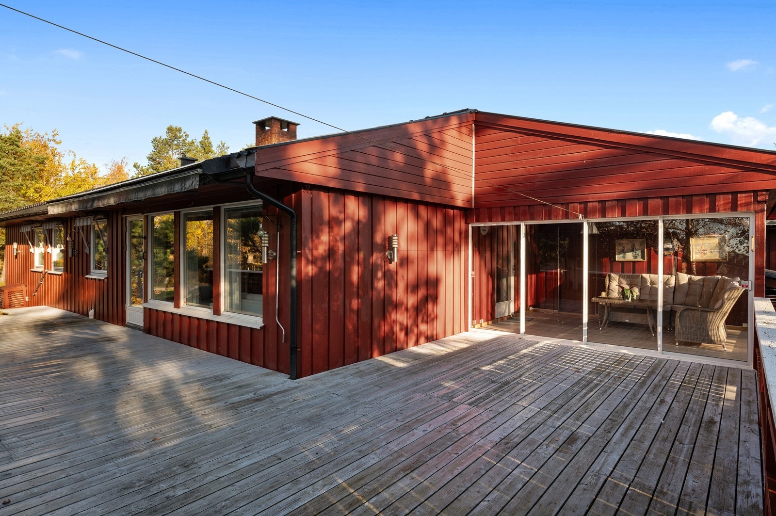 En stor terrasse strekker seg langs boligen, med en innglasset vinterhage. Galleribilde