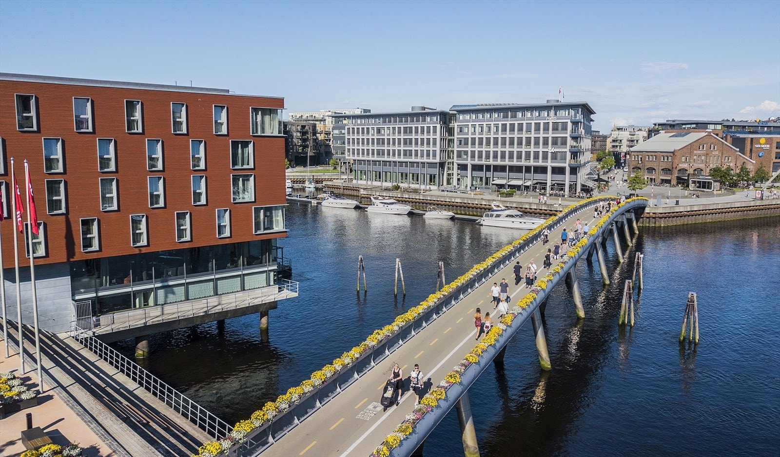 Områdebilde: Blomsterbrua - kjent for sine fargerike blomsterkasser over Nidelva om sommeren, og gir et levende og vakkert innslag i bybildet mellom Midtbyen og Bakklandet. Galleribilde