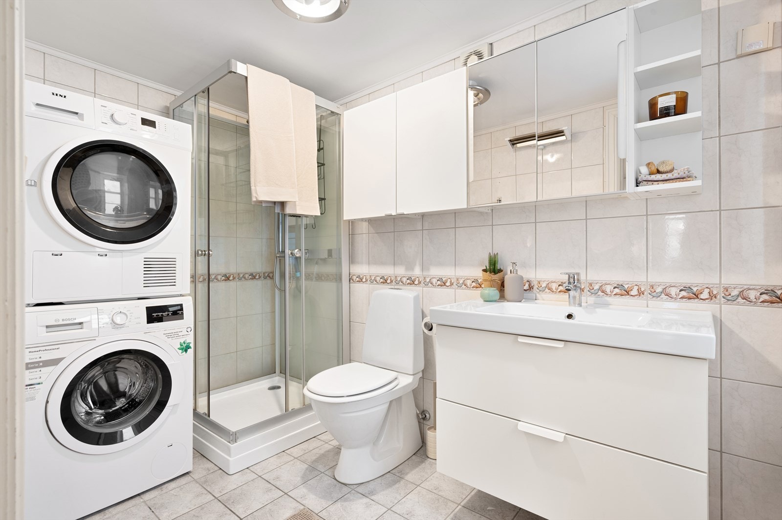 Badet er på 4,5m² med varme i det flisbelagte gulvet, flis på vegger og malte plater i himling. Innredning med servant, klosett, opplegg for vaskemaskin, dusjkabinett og mekanisk avtrekk. Galleribilde