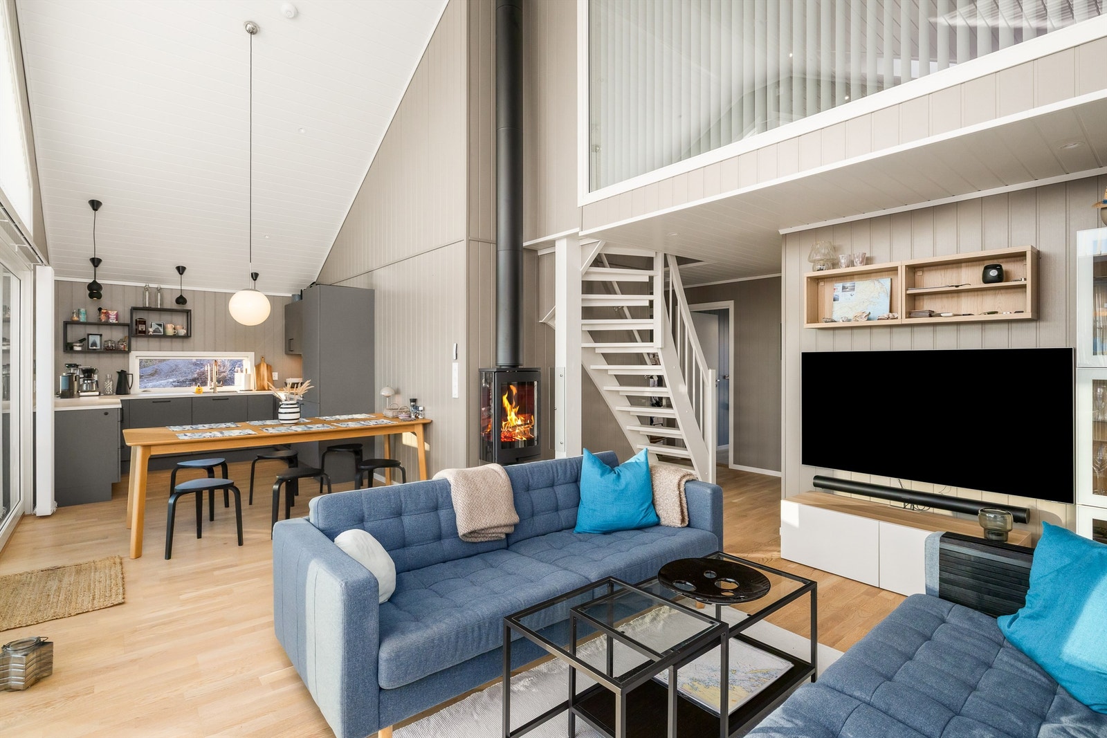 TETT PÅ NATUREN: Oppholdsrommet er åpent, lunt og intimt. Likevel virker det større, siden de store vinduene fyller hytta med naturen utenfor. Peisoven sørger for varme på kalde dager. Galleribilde