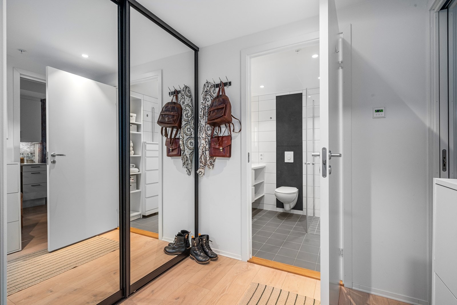 En romslig entré med skyvedørsgarderobe gir en lun velkomst med gulvvarme og dowlights i taket Galleribilde