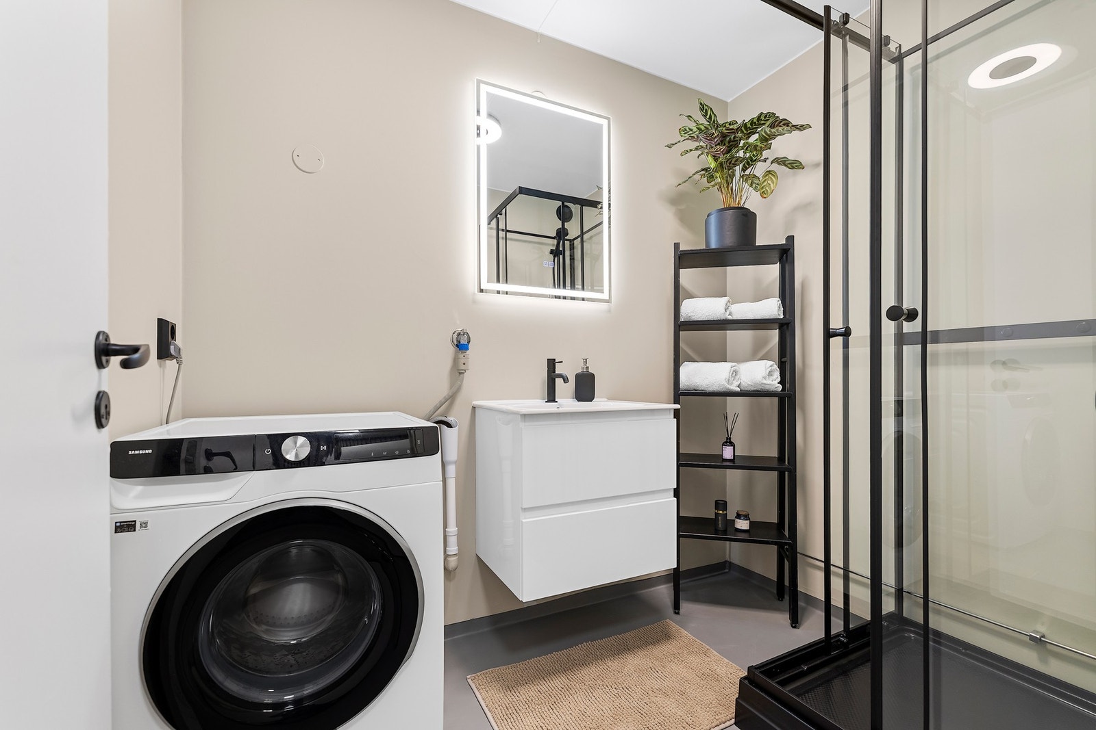 Badet har servant med skuffeseksjon, dusjkabinett og opplegg for vaskemaskin Galleribilde