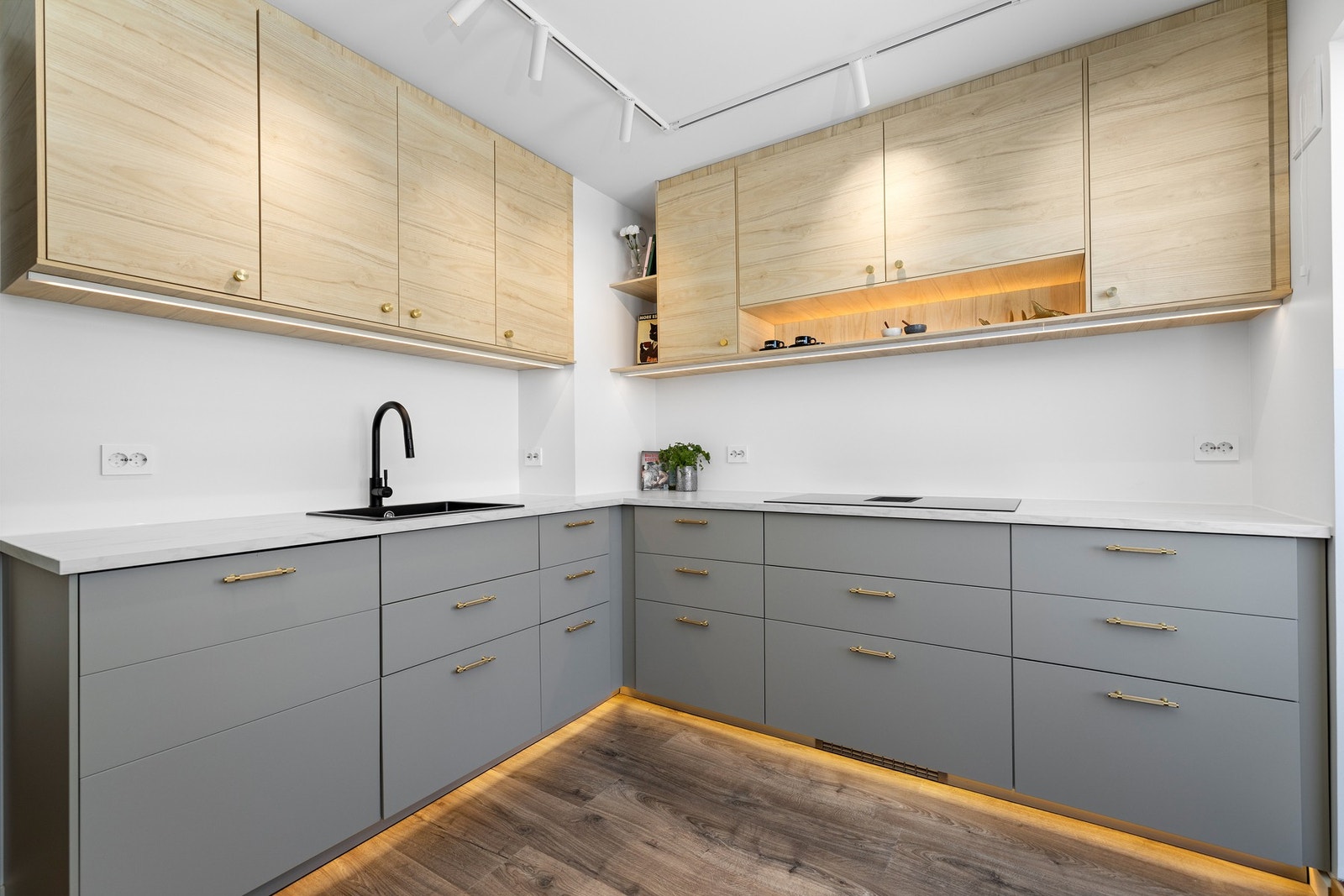 Innredningen har slette fronter i beige og trefinish, samt dekorative åpne hyller med stemningsgivende belysning Galleribilde